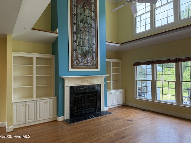 2602 Linden Ln NW, Wilson, NC 27896 - unfurnished living room with wood finished floors, ceiling fan, a high end fireplace, plenty of natural light, and a high ceiling