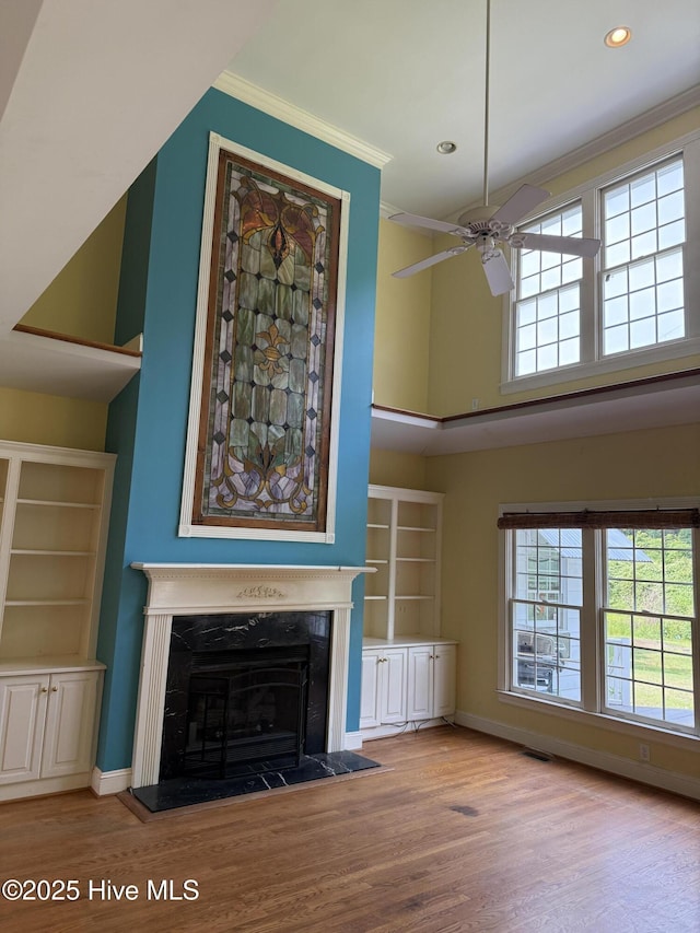 2602 Linden Ln NW, Wilson, NC 27896 - unfurnished living room featuring a ceiling fan, wood finished floors, ornamental molding, a fireplace with raised hearth, and healthy amount of natural light