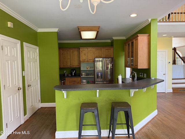 2602 Linden Ln NW, Wilson, NC 27896 - kitchen featuring stainless steel refrigerator with ice dispenser, dark countertops, dark wood-type flooring, brown cabinets, and crown molding