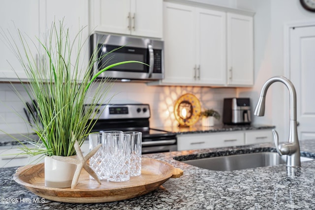 506 Esthwaite Dr SE, Leland, NC 28451 - kitchen featuring appliances with stainless steel finishes, a sink, dark stone countertops, and white cabinetry