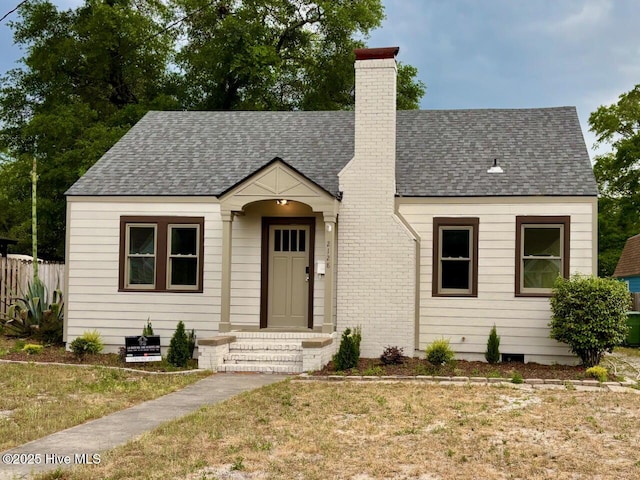 2128 Jackson St, Wilmington, NC 28401 - view of front of house featuring fence, a front lawn, a chimney, and roof with shingles