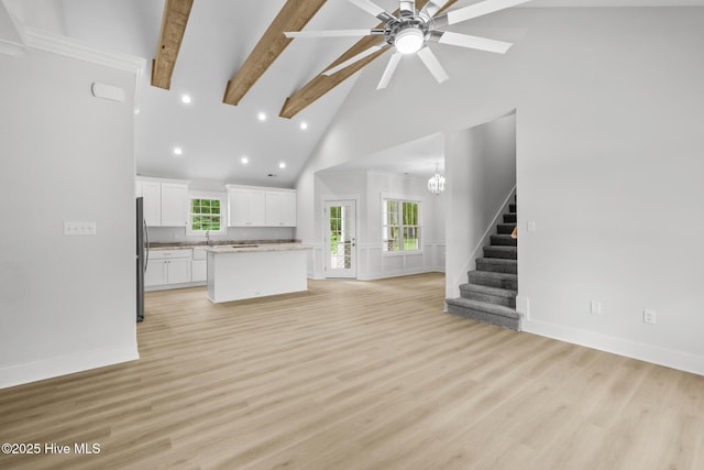 1064 Tulls Creek Rd, Moyock, NC 27958 - unfurnished living room with high vaulted ceiling, beamed ceiling, stairway, light wood finished floors, and healthy amount of natural light