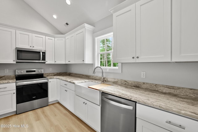 1064 Tulls Creek Rd, Moyock, NC 27958 - kitchen featuring stainless steel appliances, vaulted ceiling, white cabinets, light wood finished floors, and light stone counters