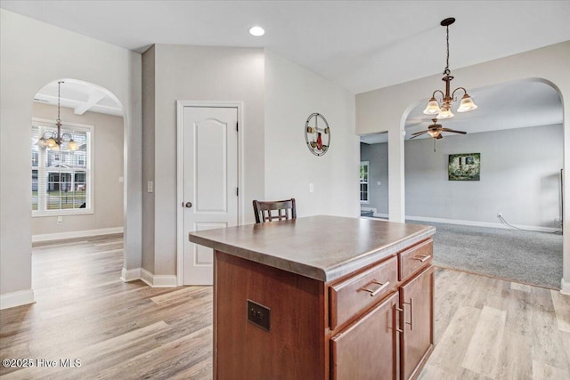  - kitchen with arched walkways, a kitchen island, and light wood-style flooring