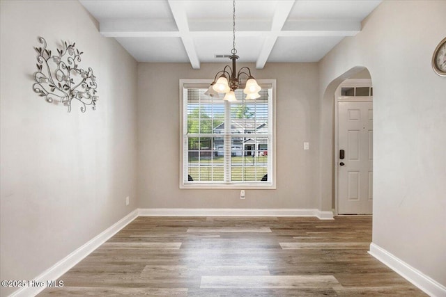  - unfurnished dining area with beam ceiling, arched walkways, a chandelier, coffered ceiling, and wood finished floors