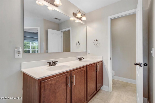  - bathroom featuring double vanity, visible vents, toilet, and a sink