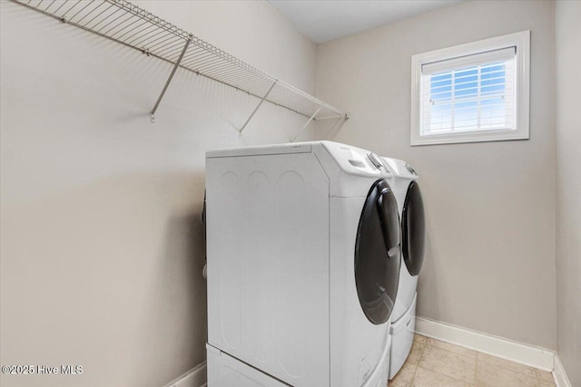  - clothes washing area with separate washer and dryer, baseboards, laundry area, and light tile patterned floors