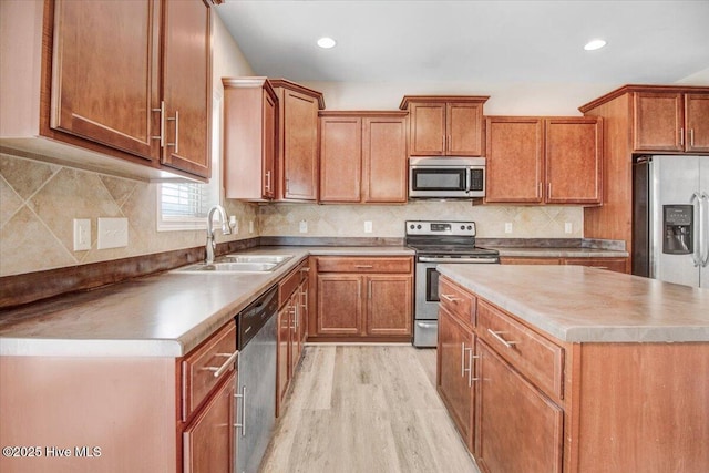  - kitchen with brown cabinets, light wood-style flooring, appliances with stainless steel finishes, and a sink