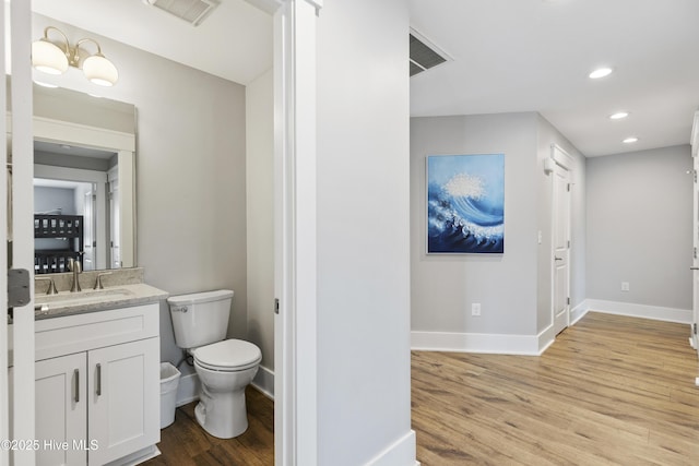 bathroom featuring baseboards, toilet, wood finished floors, and visible vents