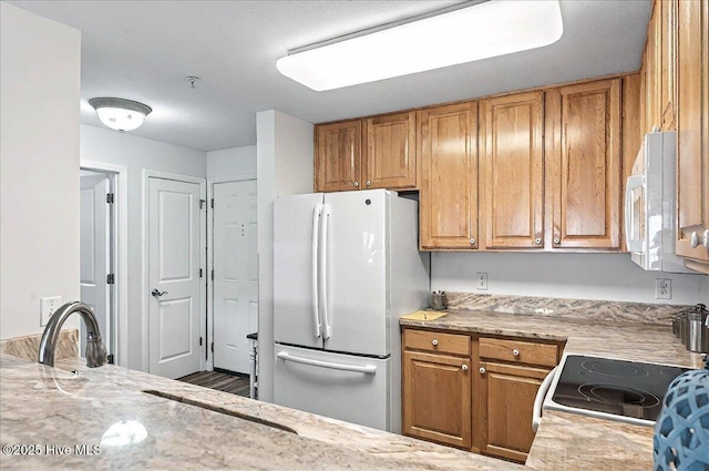 260 S Crow Creek Dr NW Lot 18, Calabash, NC 28467 - kitchen featuring light stone counters, brown cabinetry, and white appliances