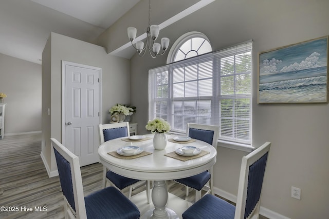 dining area featuring a chandelier, wood finished floors, baseboards, and lofted ceiling