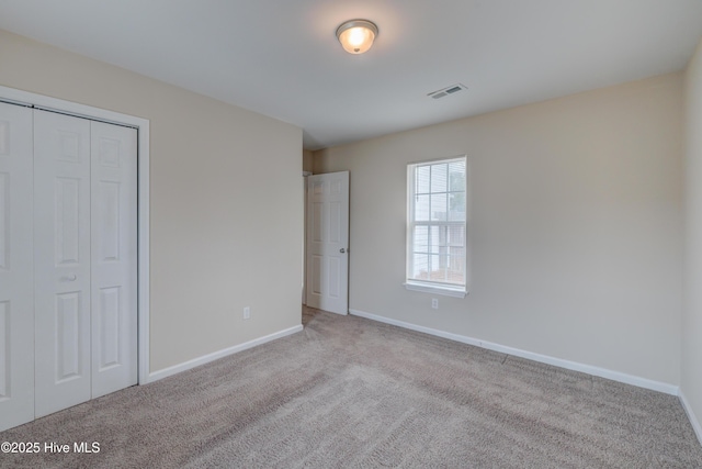 unfurnished bedroom featuring carpet, baseboards, and a closet