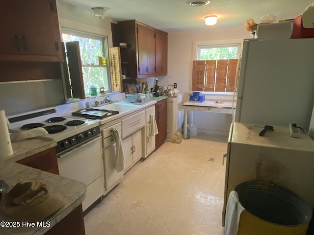 kitchen with washer / clothes dryer, light countertops, a healthy amount of sunlight, and white appliances