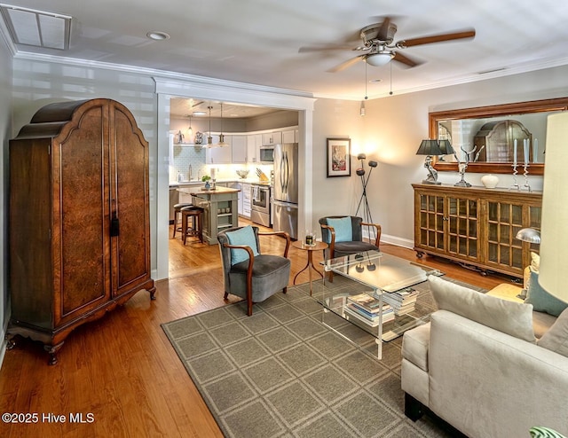 2111 Gibson Ave, Wilmington, NC 28403 - living area with crown molding, ceiling fan, baseboards, wood finished floors, and visible vents
