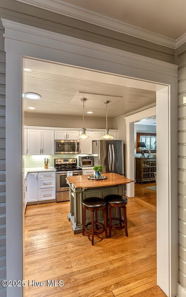 2111 Gibson Ave, Wilmington, NC 28403 - kitchen with a toaster, a breakfast bar, light wood-type flooring, white cabinetry, and appliances with stainless steel finishes