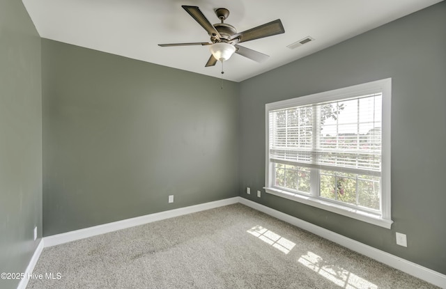 spare room with carpet, visible vents, a ceiling fan, and baseboards