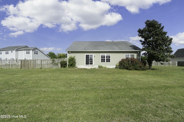 back of property featuring a yard, roof with shingles, and fence