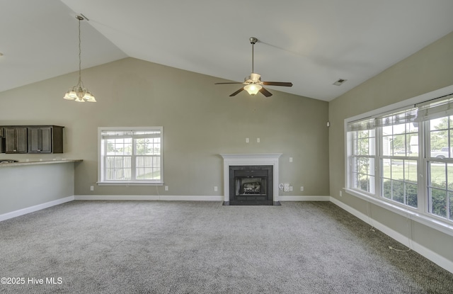 unfurnished living room featuring a fireplace with flush hearth, visible vents, a wealth of natural light, and ceiling fan with notable chandelier