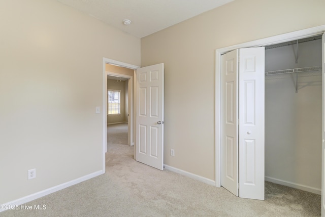 unfurnished bedroom with baseboards, carpet flooring, and a closet