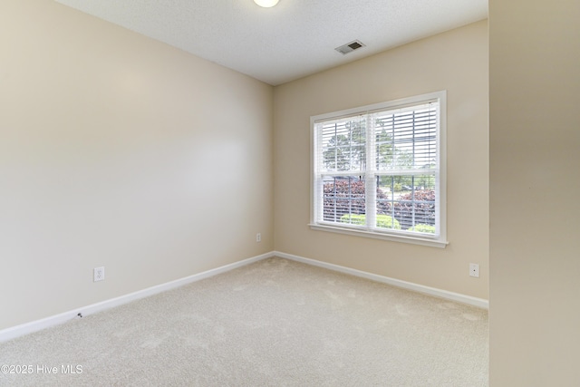 carpeted spare room with visible vents and baseboards