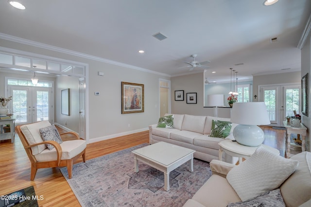 living room featuring crown molding, french doors, light wood-style flooring, and plenty of natural light
