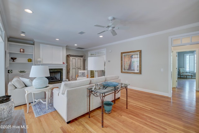 living area featuring ornamental molding, ceiling fan, baseboards, and light wood-style floors