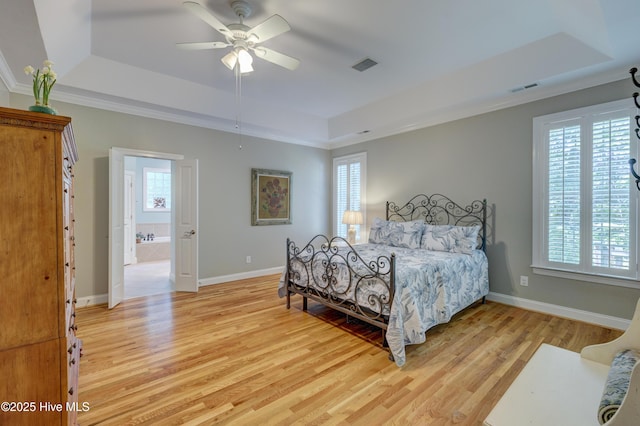 bedroom featuring light wood finished floors, a raised ceiling, and visible vents