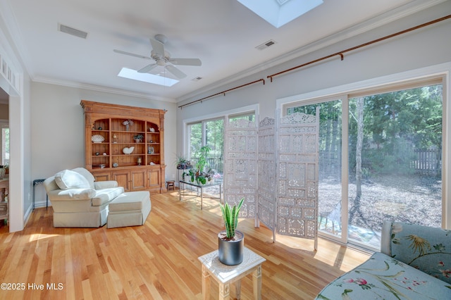 living room with a skylight, visible vents, a ceiling fan, and wood finished floors
