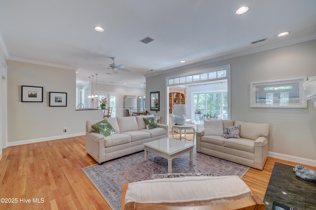 living area with visible vents, light wood-type flooring, crown molding, and recessed lighting