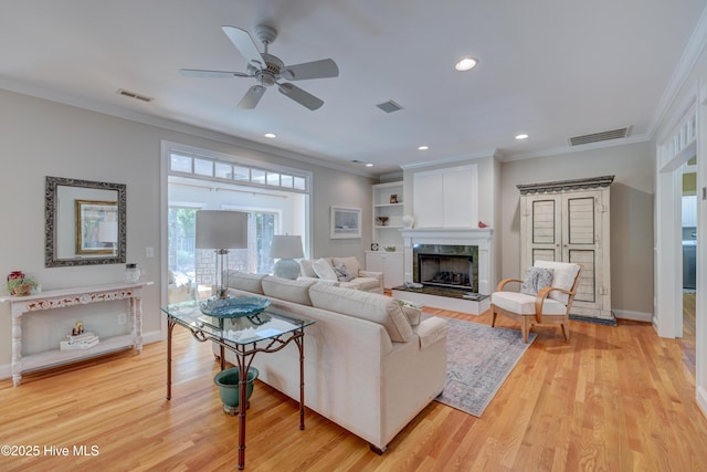 living room featuring visible vents, ornamental molding, and light wood-style floors