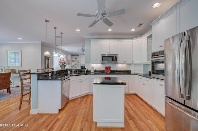 kitchen featuring a sink, appliances with stainless steel finishes, ceiling fan, light wood-style floors, and a peninsula