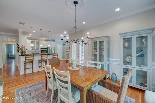dining room featuring a wealth of natural light, visible vents, light wood-type flooring, and crown molding