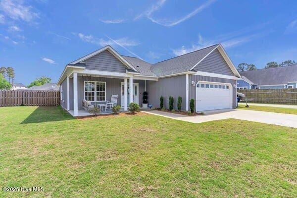 ranch-style house with covered porch, fence, a garage, driveway, and a front yard