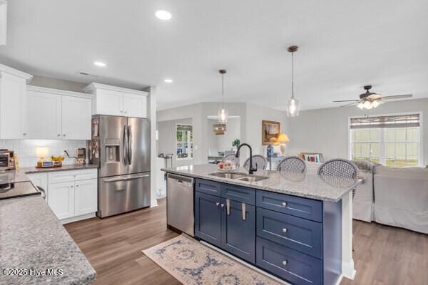 kitchen with a sink, white cabinets, a wealth of natural light, and stainless steel appliances