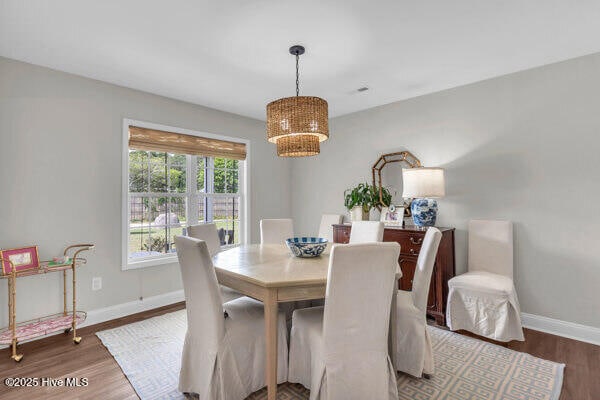 dining area with a chandelier, baseboards, and wood finished floors