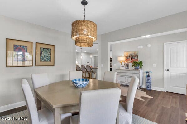 dining area featuring a notable chandelier, wood finished floors, and baseboards