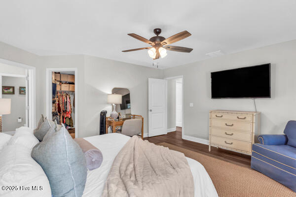 bedroom with wood finished floors, a closet, ceiling fan, baseboards, and a spacious closet