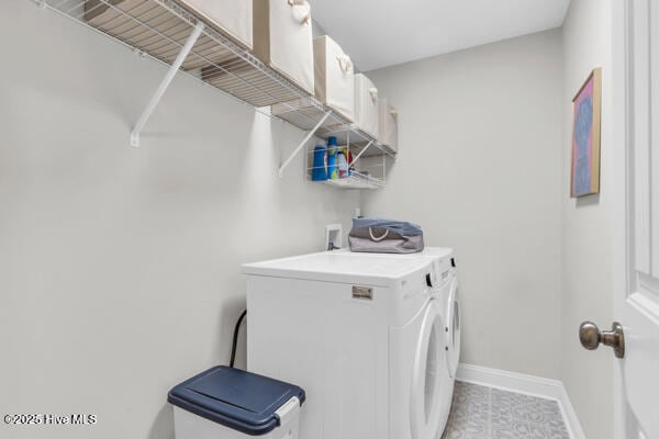 clothes washing area with baseboards, light tile patterned floors, washer and clothes dryer, and laundry area