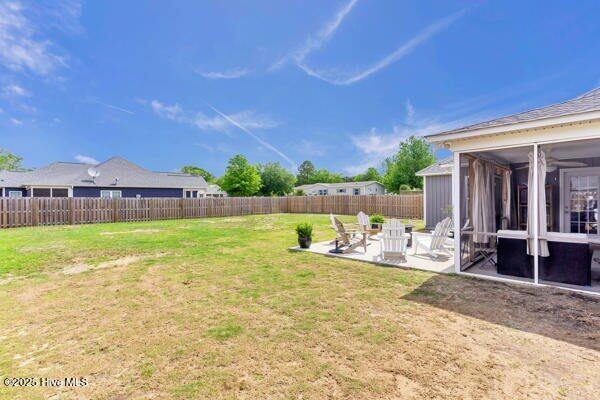 view of yard with a sunroom, a patio, and a fenced backyard