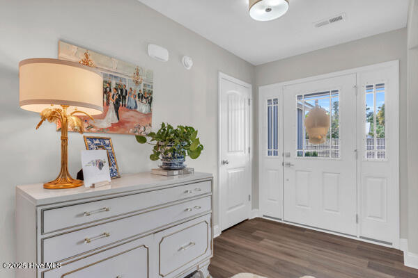 foyer with dark wood-style flooring, baseboards, and visible vents