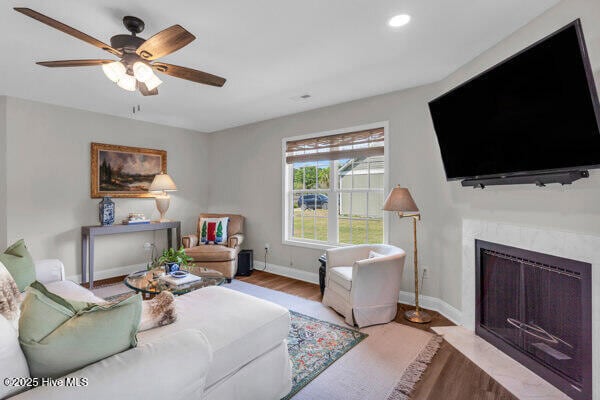 living area with recessed lighting, wood finished floors, a fireplace, baseboards, and a ceiling fan