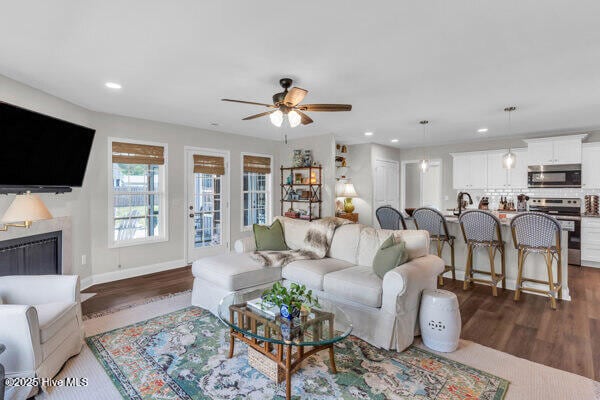 living area featuring a fireplace, a ceiling fan, dark wood-style floors, and recessed lighting