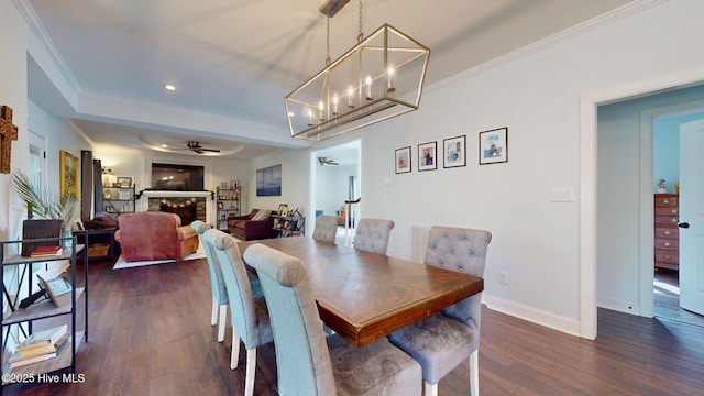 2417 Turtle Bay Dr, New Bern, NC 28562 - dining space with ornamental molding, a stone fireplace, baseboards, dark wood finished floors, and ceiling fan with notable chandelier