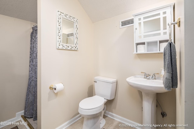 869 Driftwood Dr, Greenville, NC 27858 - full bathroom featuring toilet, a textured ceiling, lofted ceiling, baseboards, and tile patterned floors