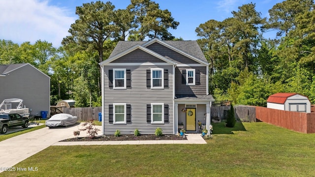 view of front facade featuring concrete driveway, a front yard, an outbuilding, and fence