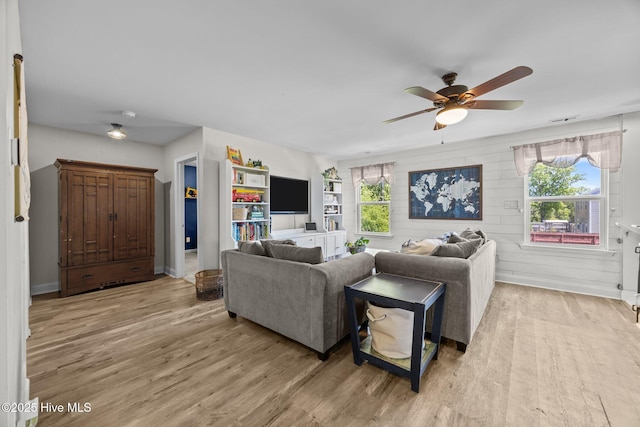 living room with baseboards, light wood-style floors, and ceiling fan