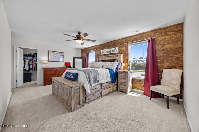 bedroom featuring light colored carpet, visible vents, a spacious closet, a ceiling fan, and baseboards