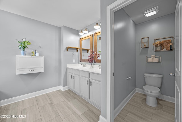 full bath with double vanity, toilet, baseboards, and wood tiled floor