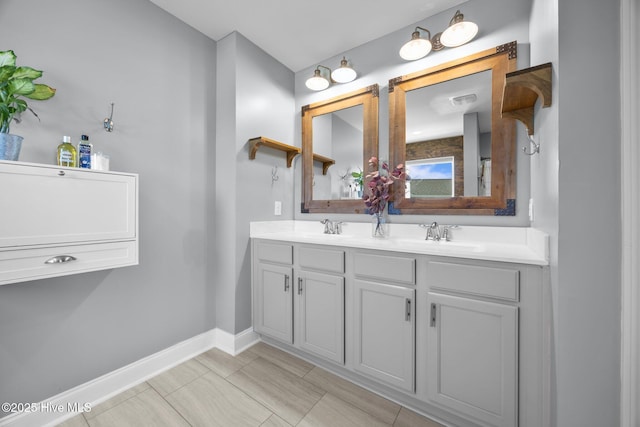 full bath featuring a sink, double vanity, and baseboards