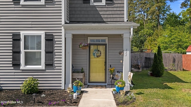 property entrance with fence and a lawn